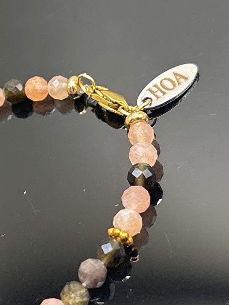 Ръчно изработена гривна от естествен слънчев камък и обсидиан с фасетирани мъниста и златни метални елементи, елегантно бижу с топъл блясък и дълбок черен контраст