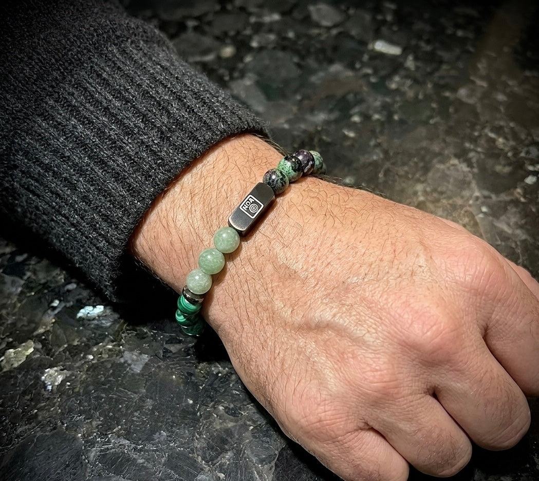 Мъжка гривна от естествени камъни – нефрит, малахит, зелен флуорит, камамба яспис и рубин в цоизит, ръчно изработена от House of Astrology. Балансиращ артефакт за растеж, вътрешна сила и хармония.