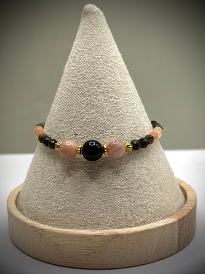 Ръчно изработена гривна от естествен слънчев камък и обсидиан с фасетирани мъниста и златни метални елементи, елегантно бижу с топъл блясък и дълбок черен контраст