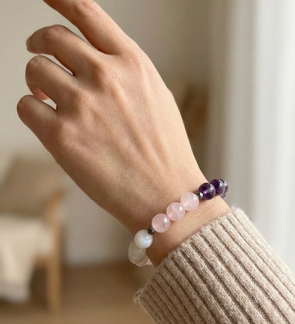 Гривна HOA „Седма Чакра“ от естествени камъни, ръчно изработена. Аметист, розов кварц и лунен камък в нежна композиция за баланс и яснота.