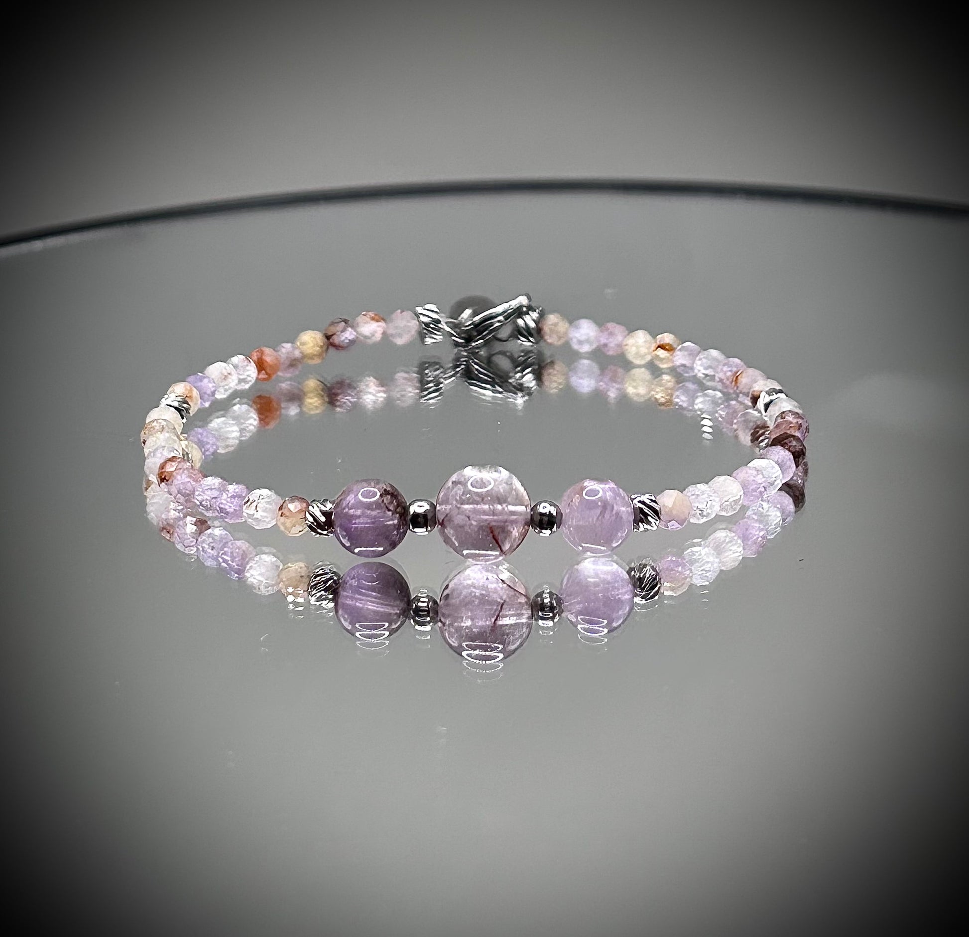 Луксозна дамска гривна от рядък камък Мелодит (Super Seven) с фасетирани кристали и елементи от медицинска стомана. Артефакт за духовно пробуждане от колекция Lemurian Bloodline на House of Astrology.