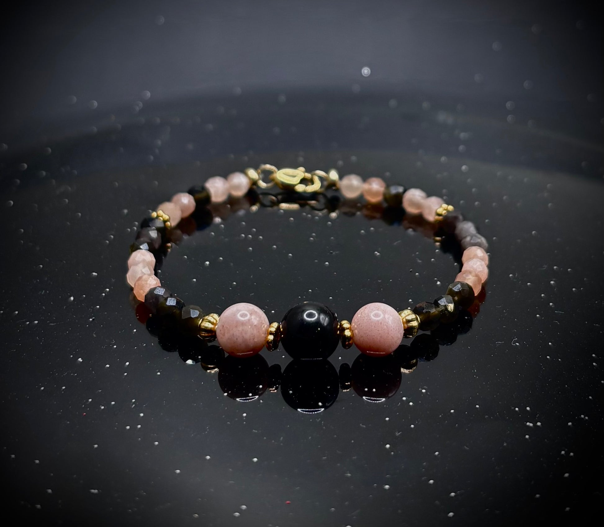Ръчно изработена гривна от естествен слънчев камък и обсидиан с фасетирани мъниста и златни метални елементи, елегантно бижу с топъл блясък и дълбок черен контраст