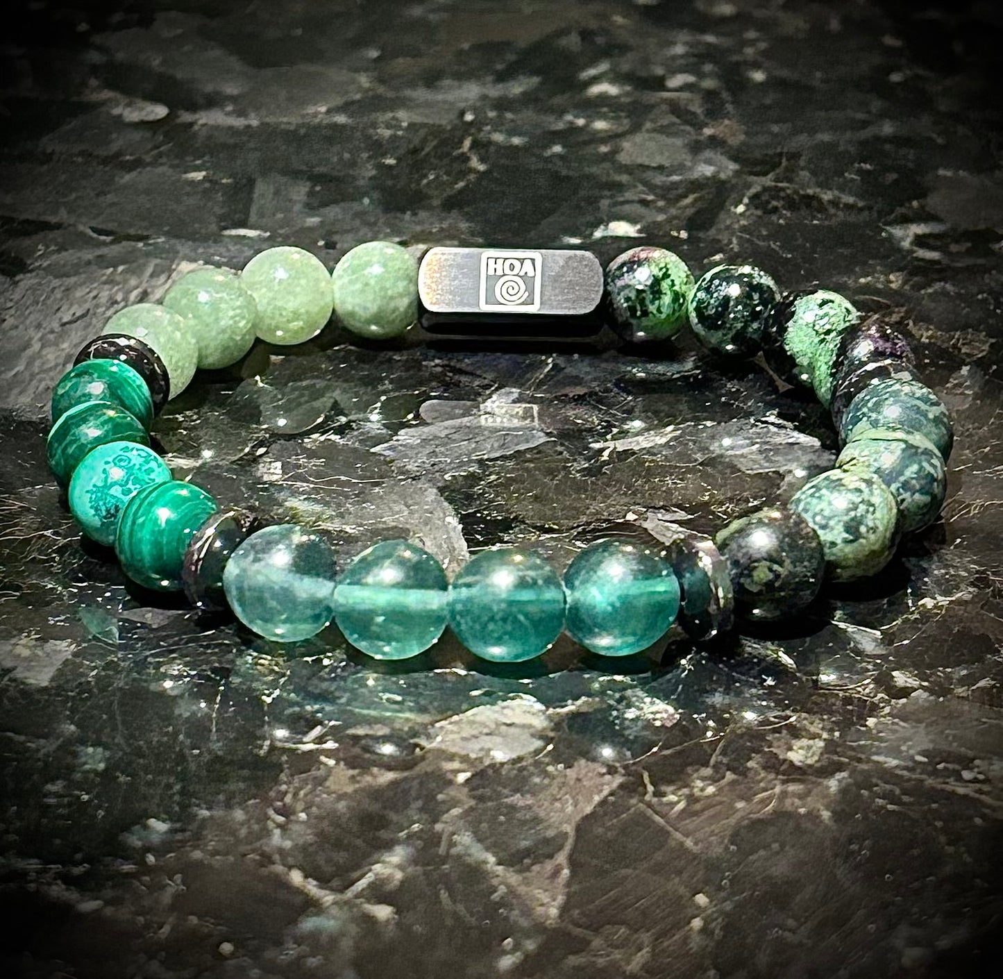 Мъжка гривна от естествени камъни – нефрит, малахит, зелен флуорит, камамба яспис и рубин в цоизит, ръчно изработена от House of Astrology. Балансиращ артефакт за растеж, вътрешна сила и хармония.