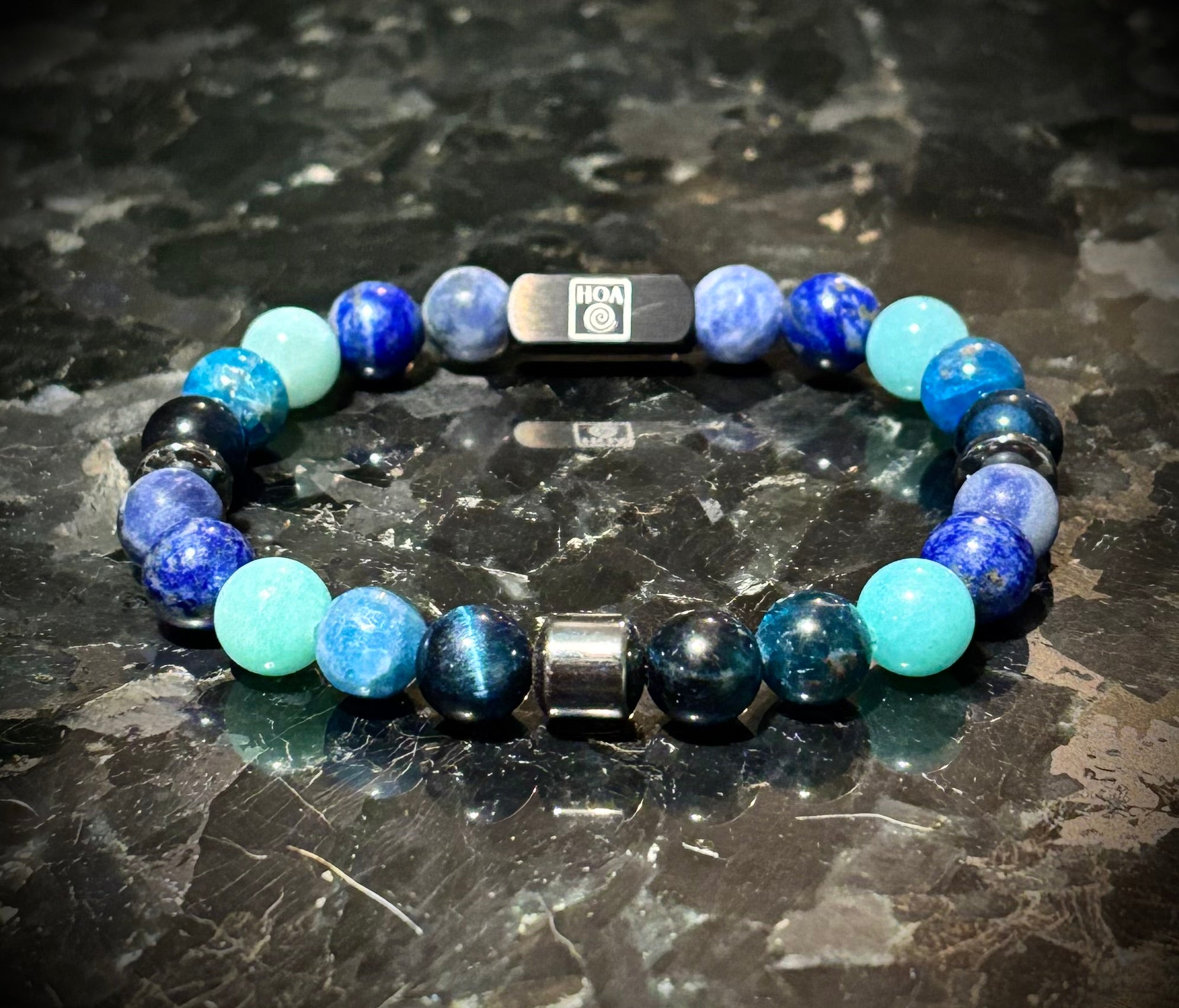 Мъжка гривна от естествени камъни – соколово око, амазонит, содалит, лапис лазули и апатит, ръчно изработена от House of Astrology. Артефакт за ясно изразяване, увереност и силна комуникация.