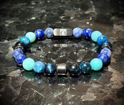 Мъжка гривна от естествени камъни – соколово око, амазонит, содалит, лапис лазули и апатит, ръчно изработена от House of Astrology. Артефакт за ясно изразяване, увереност и силна комуникация.