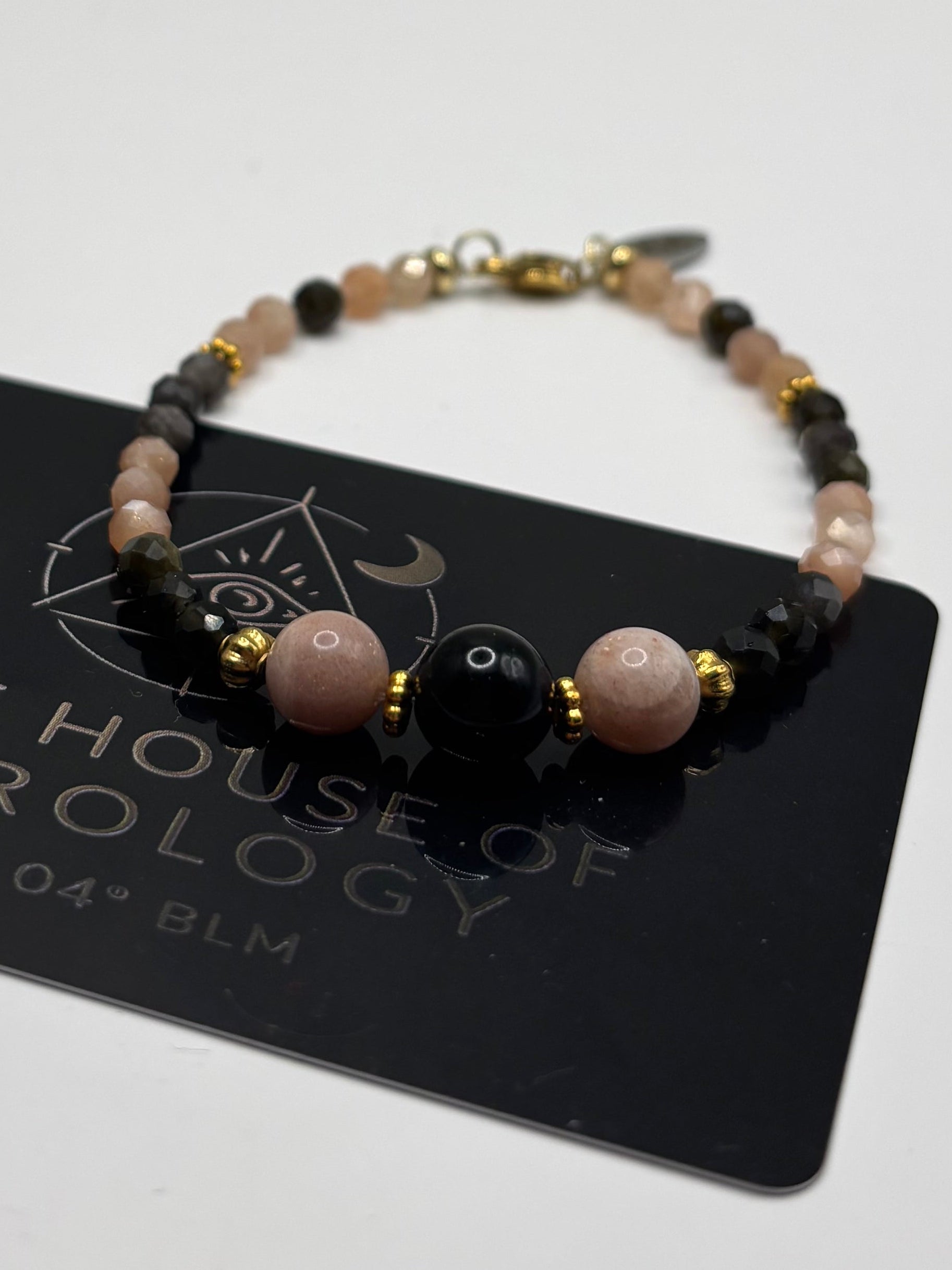 Ръчно изработена гривна от естествен слънчев камък и обсидиан с фасетирани мъниста и златни метални елементи, елегантно бижу с топъл блясък и дълбок черен контраст