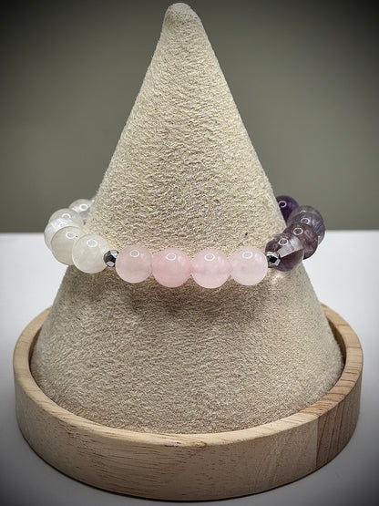 Гривна HOA „Седма Чакра“ от естествени камъни, ръчно изработена. Аметист, розов кварц и лунен камък в нежна композиция за баланс и яснота.